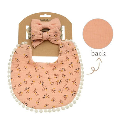 Baby floral waterproof bib and matching bows headband set in peach color, featuring pom-pom trim and floral patterns.