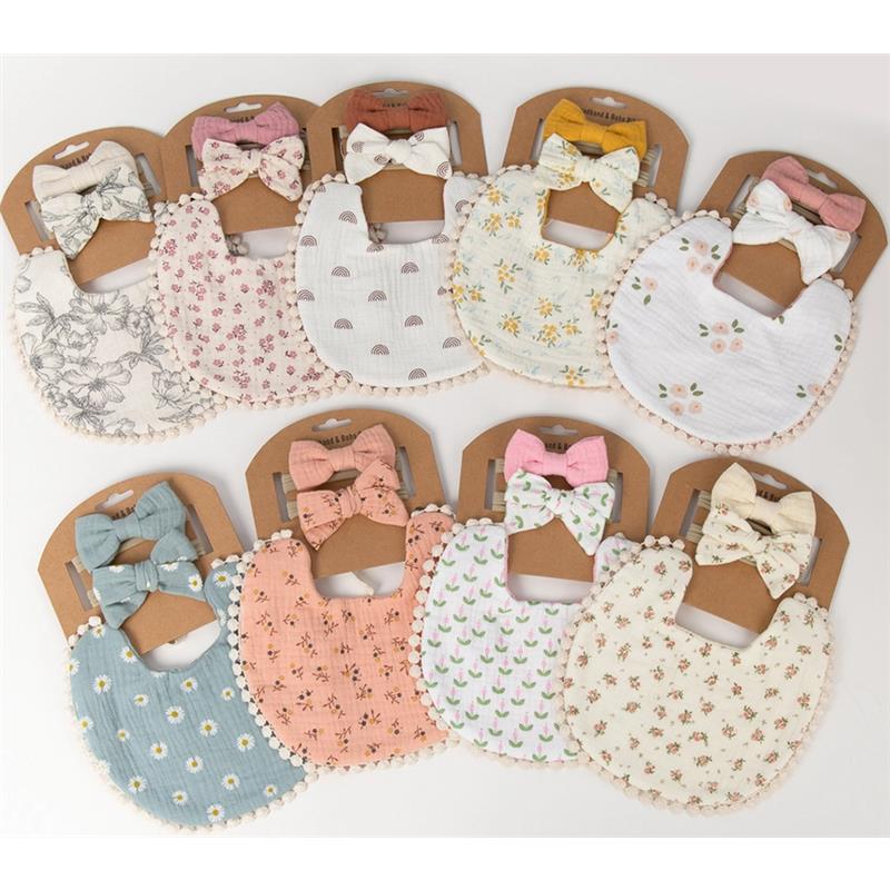 Set of ten baby bibs with coordinating bows, featuring floral and patterned designs in soft colors, displayed on brown tags.