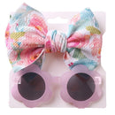 Floral patterned headband paired with pink flower-shaped sunglasses for baby girls. Ideal summer accessories.