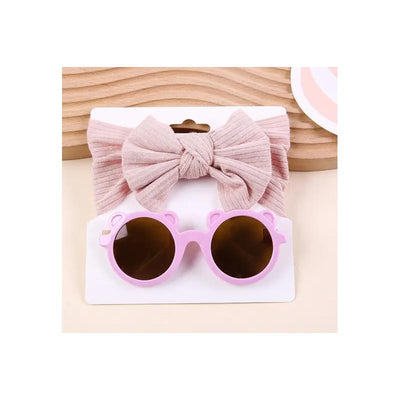 Baby sunglasses with a pink bear-shaped frame and dark lenses, paired with a soft, light pink headband bow.