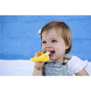 Infant happily uses a yellow Baby Banana Brush, designed for teething and brushing, against her gums.