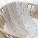 Two soft jersey swaddles in neutral tones, featuring rainbows and playful sloths, folded in a crib.