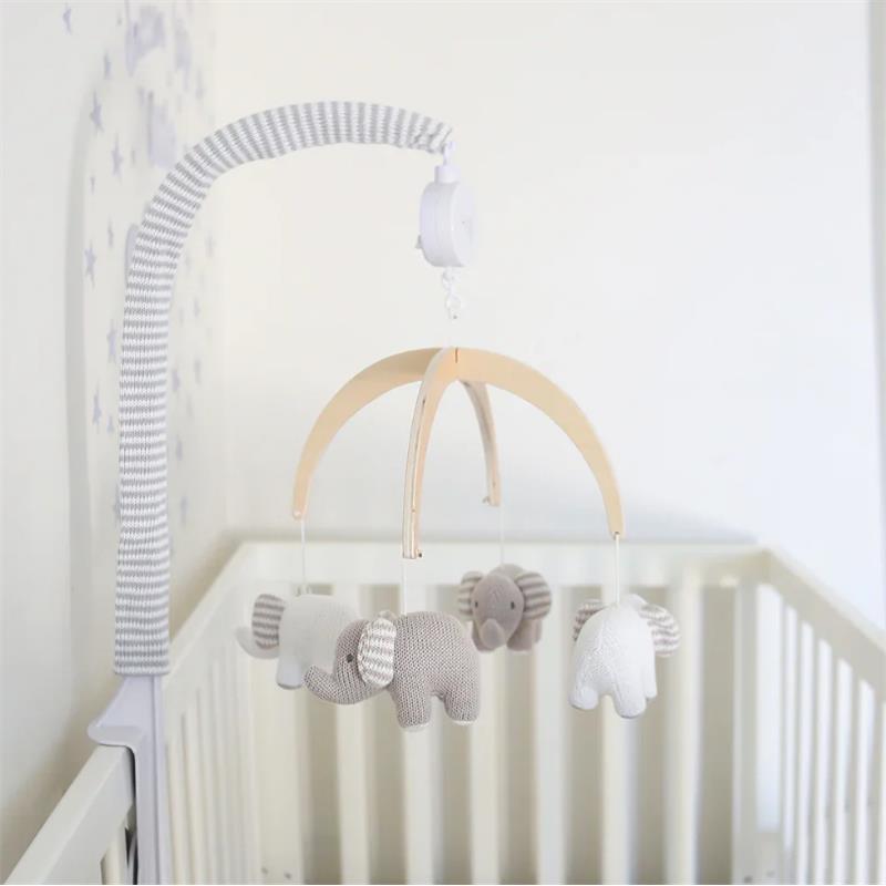 Musical mobile featuring knitted elephants in gray and white, suspended from a wooden frame above a crib.