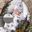 Newborn baby swaddled in a forest-themed blanket and hat, with an introduction card for recording details.