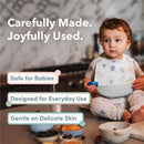 Loulou Lollipop Silicone Bib in Unicorn Ballet design worn by a toddler, with text highlighting its safety and usability features.
