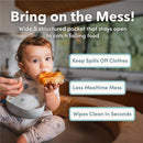Silicone bib on a toddler catching food, highlighting features like a wide pocket to reduce mess during mealtime.