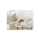 Macrobaby Baby Room Powder Spray bottle on a wooden table beside a lamp and decorative objects in a cozy room setting.