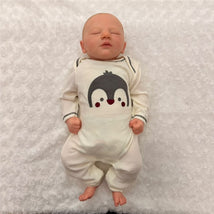 Macrobaby Reborn Doll named Jaxson, featuring white vinyl, painted hair, closed eyes, and dressed in a penguin-themed onesie.