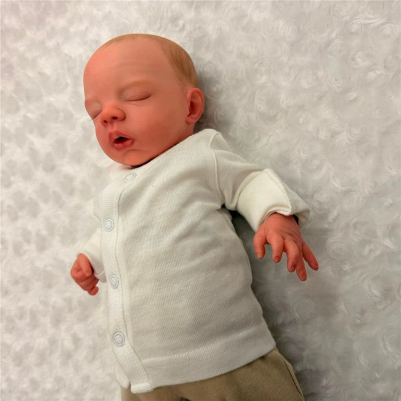 Reborn doll named Megan, made of white vinyl, with painted hair, opened blue eyes, wearing a white onesie.