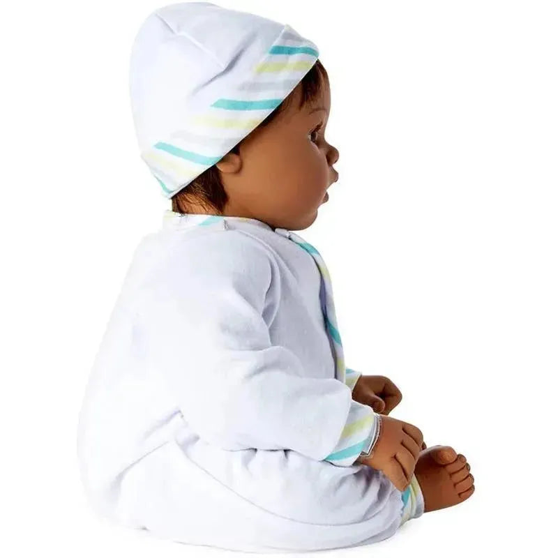 Baby doll with medium skin tone, brown eyes, and black hair, wearing a white outfit and striped hat, sitting sideways.