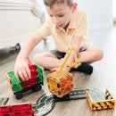 A child plays with a 32-piece Magnatiles set, building structures with magnetic blocks and toys, including a yellow crane and trucks.
