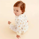 Baby wearing a magnetic coverall with Dumbo and circus-themed designs, sitting and looking over their shoulder.