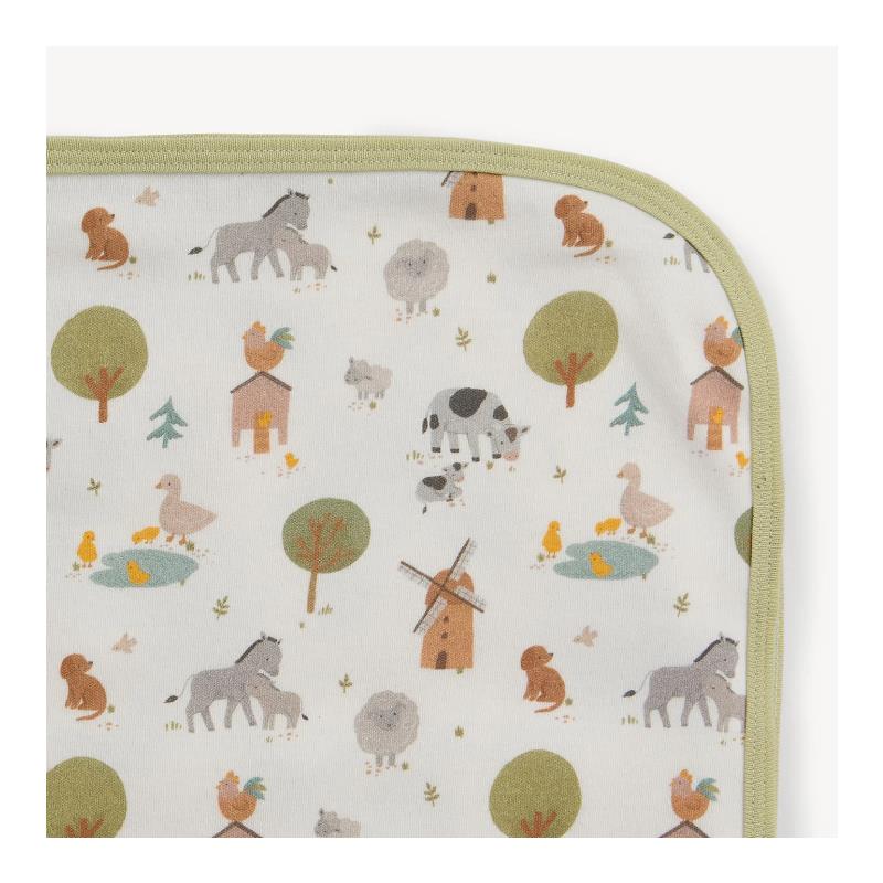 Organic cotton blanket featuring a whimsical farm animal pattern with cows, sheep, ducks, and trees, edged in green.
