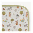 Organic cotton blanket featuring a whimsical farm animal pattern with cows, sheep, ducks, and trees, edged in green.