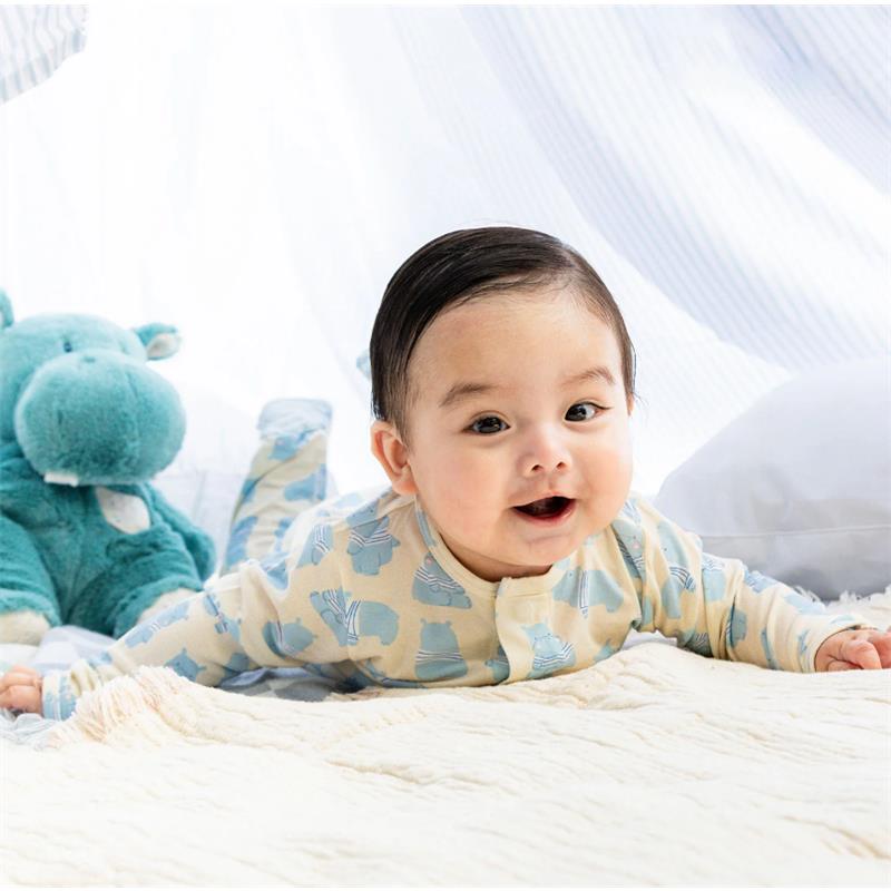 Baby wearing a Magnetic Me Pudgemuffin Modal Footie with a blue animal print, smiling while playing on a blanket next to a plush hippo.