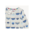 Modal coverall with a playful print of blue menorahs and dreidels, featuring a colorful trim along the neckline.