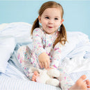 Toddler in a floral-patterned modal convertible coverall, playfully holding a stuffed bunny on a bed.