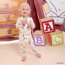Toddler wearing Magnetic Me Toy Story Woody & Friends long sleeve pajamas, smiling with colorful building blocks in the background.