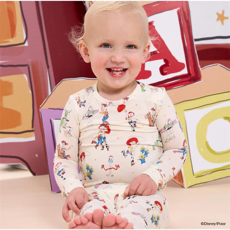 Toddler wearing Magnetic Me Toy Story Woody & Friends long sleeve pajama, smiling, with colorful character prints.