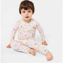 A child sits cross-legged wearing a long-sleeve pajama set decorated with colorful doodles on a light background.