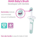 2-pack of MAM baby toothbrushes in pink, designed for 6 months+, featuring a non-slip handle and red bristles to indicate toothpaste amount.