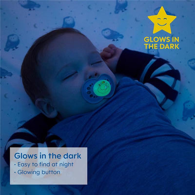 Baby sleeping with a glowing blue Mam pacifier featuring a smiling face, on a patterned blanket with owls.