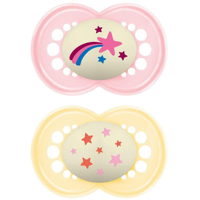 Two Mam Original Night Pacifiers: one pink with a rainbow and star design, and one yellow with multicolored stars, both glow in the dark.
