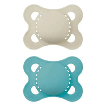Two matte unisex pacifiers in beige and blue, designed for children aged 16 months and older, showcasing a rounded shape and ventilation holes.