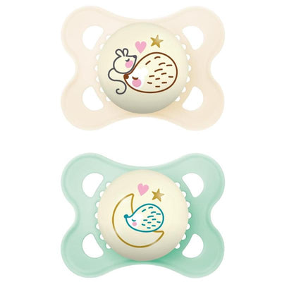 Two Mam pacifiers designed for infants aged 0-6 months; one features a sleeping hedgehog, the other a crescent moon.