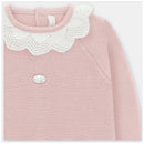 Baby pink long romper with feet, featuring a white crocheted collar and a decorative metal tag on the front.