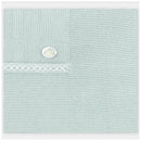 Light pink knit blanket featuring a decorative button and intricate stitching detail.