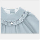 Dress in blue-grey fabric featuring a ruffled collar and decorative stitching, with a button closure at the back.