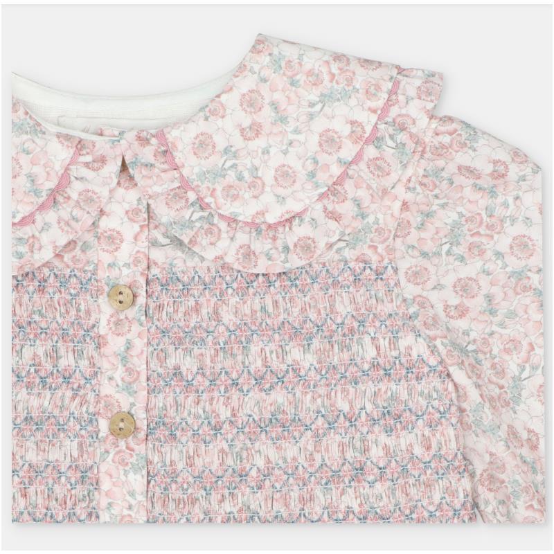 Woven dress featuring a floral all-over print, smocking detail, and a rounded collar with button closure.