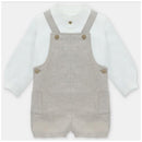 White long-sleeve shirt layered under a beige overall with two front pockets and button details.