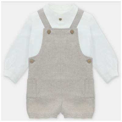 White long-sleeve shirt layered under a beige overall with two front pockets and button details.