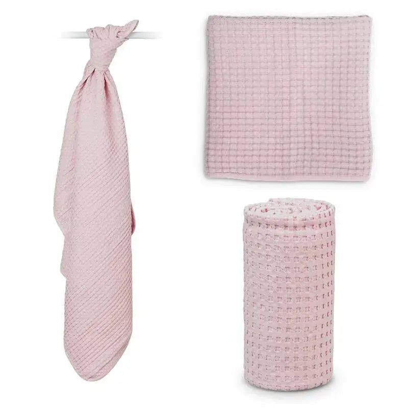 Waffle blanket in ballet slipper pink, displayed in three forms: hanging, flat, and rolled. Soft texture and versatile design.