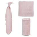 Waffle blanket in ballet slipper pink, displayed in three forms: hanging, flat, and rolled. Soft texture and versatile design.