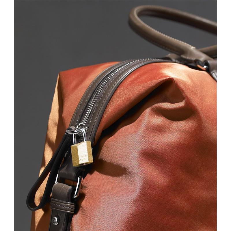 Brass Master Lock secured on a brown and orange bag, highlighting the zipper and strap details.
