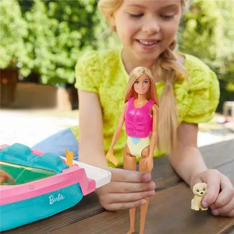 Barbie doll wearing a pink life vest, with a toy boat and small dog, as a girl plays nearby.