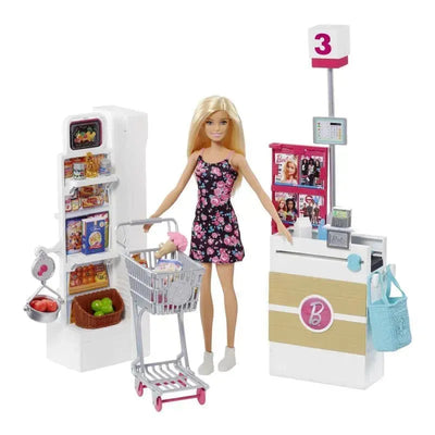 Barbie doll in a floral dress stands at a checkout counter, pushing a shopping cart filled with groceries beside a refrigerator.