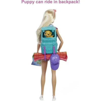 Barbie doll with a turquoise backpack holding a puppy, carrying a sleeping bag and a map, ready for camping.
