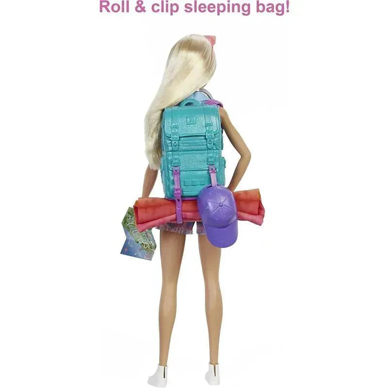 Barbie doll with long blonde hair, wearing a backpack, holding a camping map, and carrying a sleeping bag and cap.