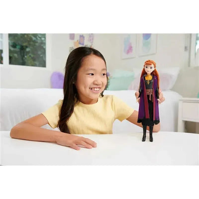A girl smiles while holding a Mattel Disney Frozen 2 Core Doll of Anna, showcasing her detailed costume and features.