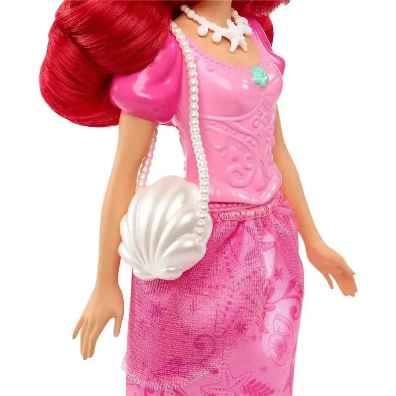 Disney Princess Ariel doll featuring a pink top, pearl necklace, and a shell-shaped handbag.