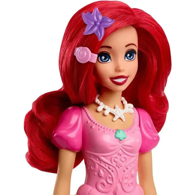 Disney Princess Ariel doll with long red hair, wearing a pink dress and a starfish necklace, smiling cheerfully.
