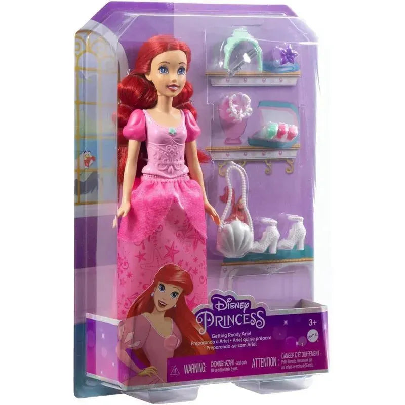 Disney Princess Ariel doll in a pink dress, featuring accessories like shoes and decorative items in the background.