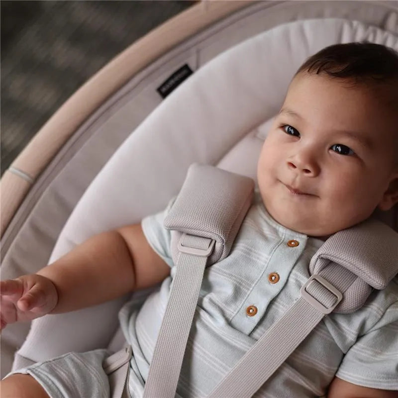 Baby sitting comfortably in a Maxi-Cosi Cassia Swing, wearing a light blue outfit with buttons, smiling.
