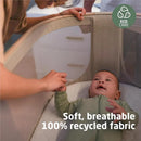 Maxi-Cosi Iora Bassinet in Classic Oat, featuring a baby in a breathable, sustainable fabric environment, with hands gently interacting.