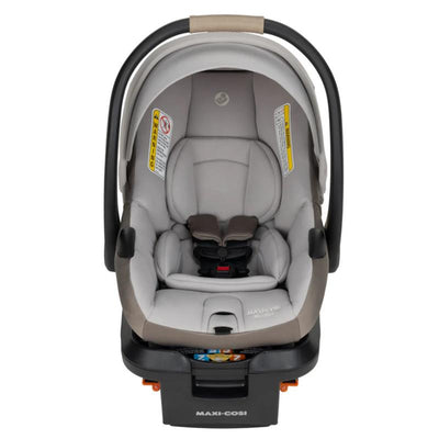 Maxi-Cosi Mico Pro+ infant car seat in oyster shell color, featuring a padded interior, harness system, and safety warning labels.
