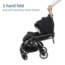 Maxi-Cosi Oxford Cabin Lightweight Travel Stroller in Truffle, shown in a folded position with a hand grasping the handle.